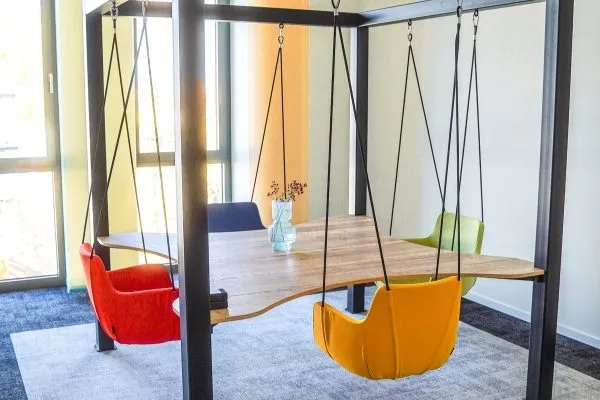 Besprechungstisch mit bunten Hängeschaukeln als Sitzgelegenheit in einem modernen Büro