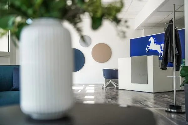Weiße Vase im Vordergrund, im Hintergrund Empfangstresen mit VGH-Logo
