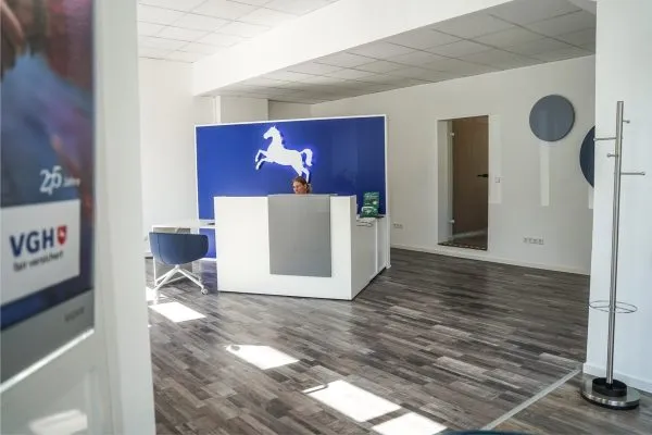 Empfangsbereich der VGH mit Firmenlogo an blauer Wand und weißem Empfangstresen