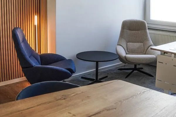 Blauer und beiger Loungesessel an einem runden Tisch mit Stehlampe im Hintergrund