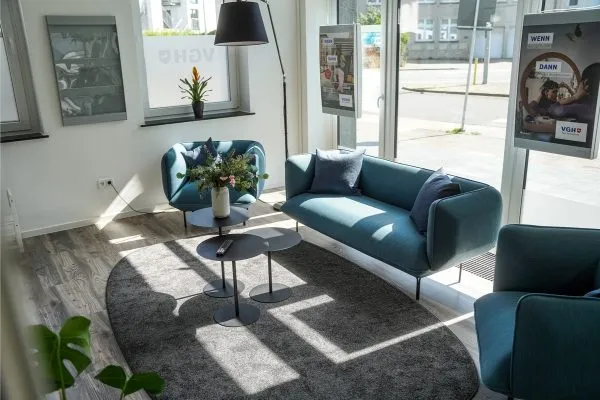 Renovierter heller Raum mit petrolfarbenem Sofa nach dem Umbau