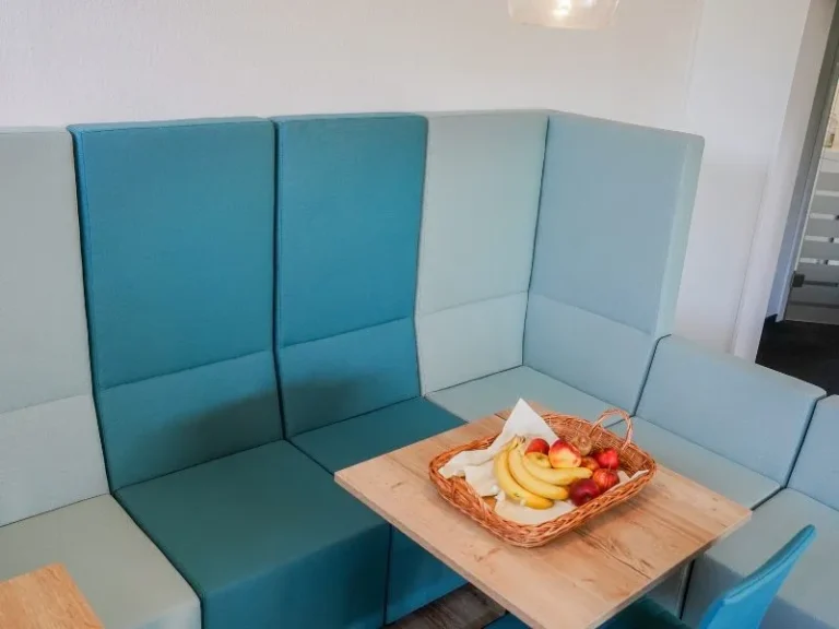 Türkisfarbene Sitzecke mit Holztisch und einem Korb frischem Obst