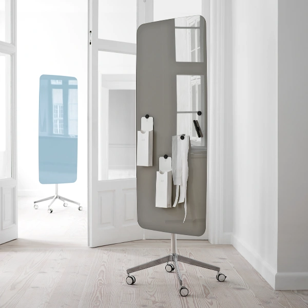 Graues Lintex Mood Mobile Whiteboard auf Rollen mit magnetisch befestigten Notizen und Zubehör in einem hellen Innenraum.